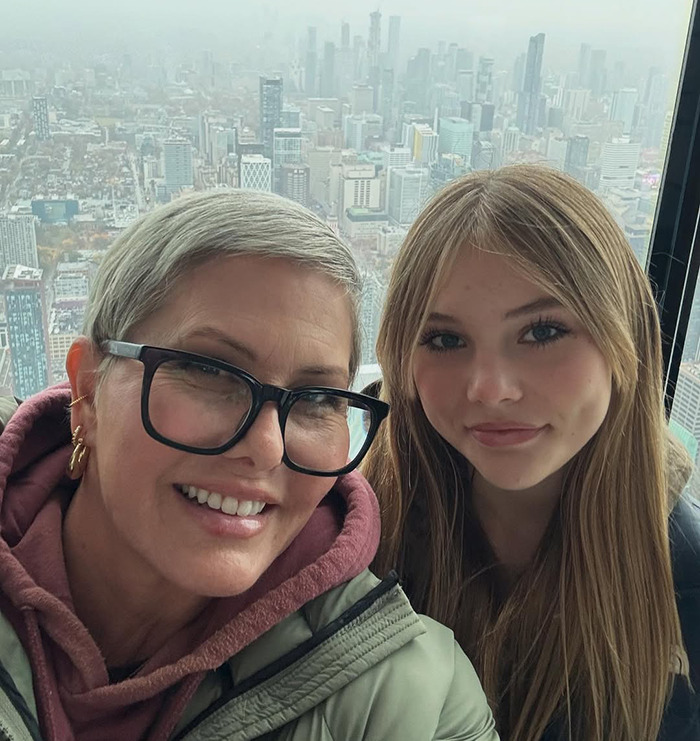 Nicole Eggert with short hair and glasses, posing with her daughter against a city skyline background. Nicole Eggert with short hair and glasses, posing with her daughter against a city skyline background.