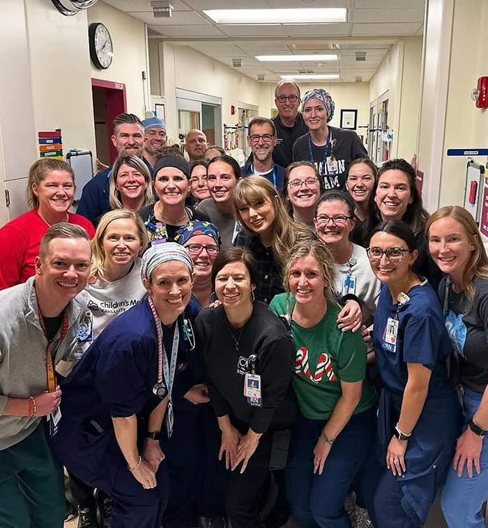 Taylor Swift visiting a children's hospital, pictured with a group of smiling healthcare staff and team members. Taylor Swift visiting a children's hospital, pictured with a group of smiling healthcare staff and team members.
