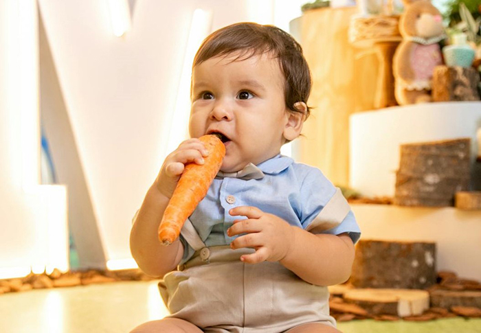 Baby in a blue shirt holding a carrot, embodying a vegetarian lifestyle. Baby in a blue shirt holding a carrot, embodying a vegetarian lifestyle.
