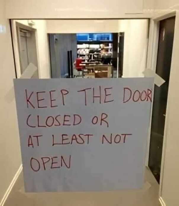Weird and absurd sign saying, "KEEP THE DOOR CLOSED OR AT LEAST NOT OPEN" taped on a glass door.