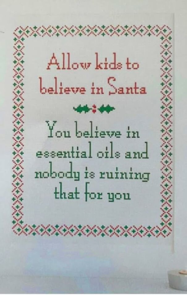 Weird sign comparing belief in Santa and essential oils, with festive border.