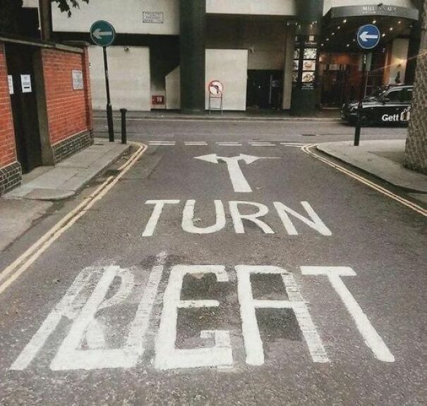 Weird and absurd road sign with misspelled "TURN RIGHT" painted on a city street.