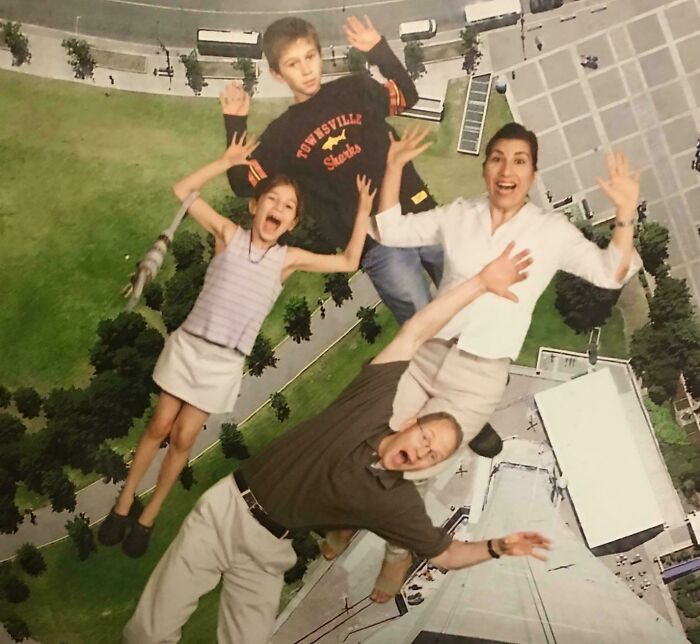 A family poses in a humorous falling illusion, capturing awkward blunder years nostalgia with wide smiles and playful gestures.