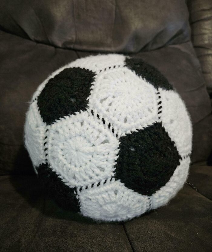 Crocheted soccer ball on a couch, showcasing amazing handicraft skills.