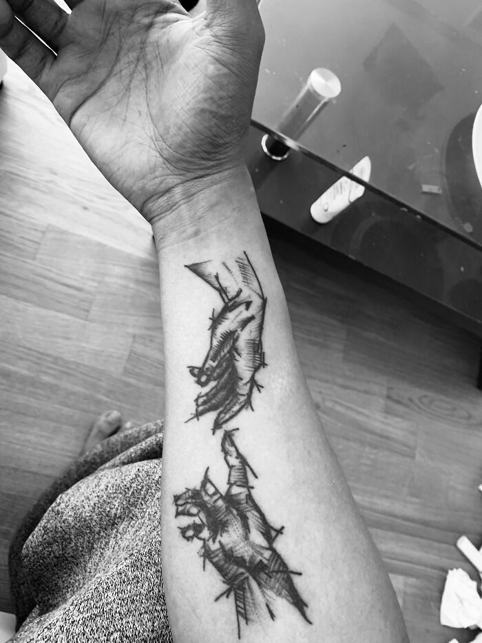 Forearm with a funny worst tattoo fail showing two sketchy hands, one reaching toward the other.