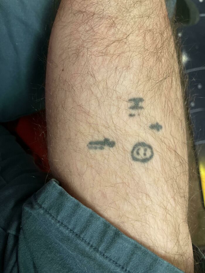 Funny worst tattoo fails: simple face and arrow tattoo on a person's leg.