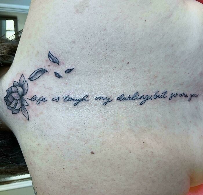 Floral tattoo with misspelled text on skin, showcasing funny worst tattoo fails.