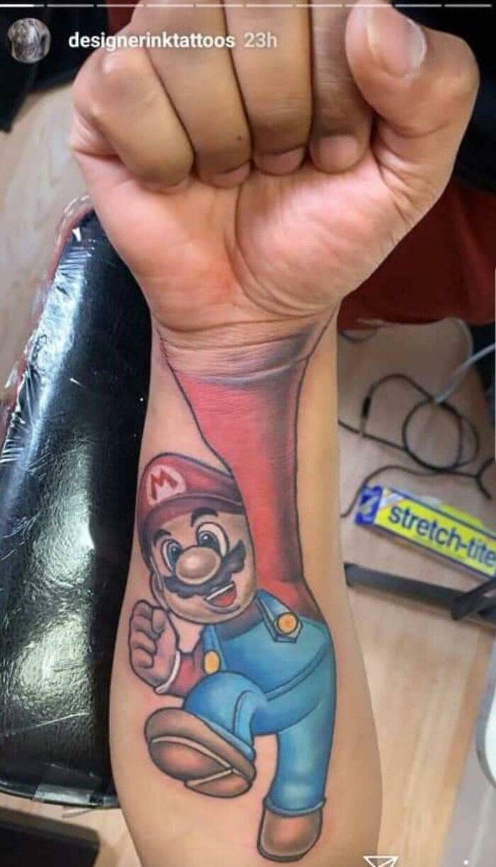 Arm tattoo of Mario appearing to climb out of a person's wrist, showcasing a funny tattoo fail.