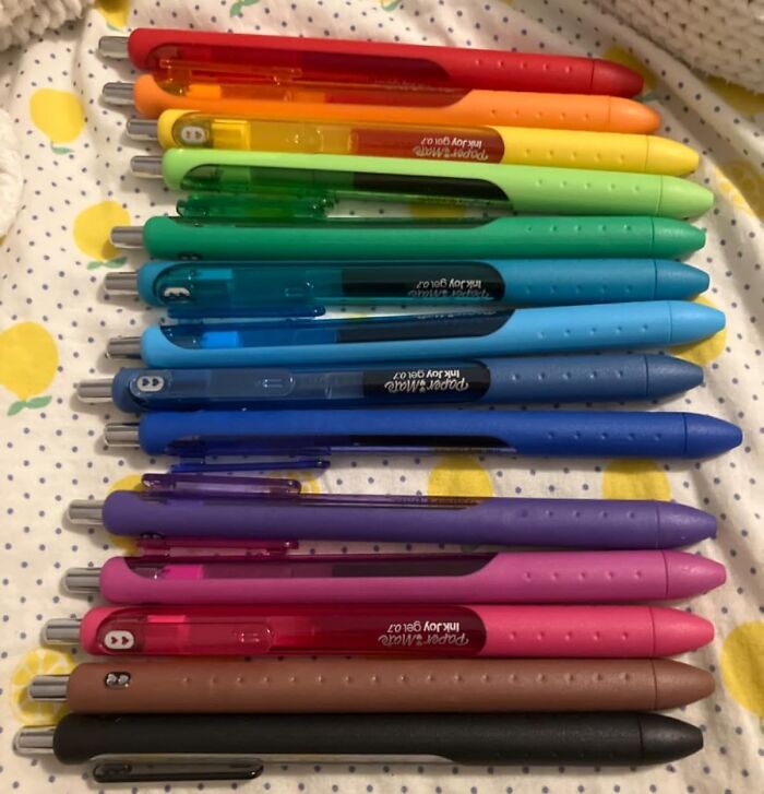 Colorful pens, ideal gifts for teachers, arranged neatly in a rainbow order.