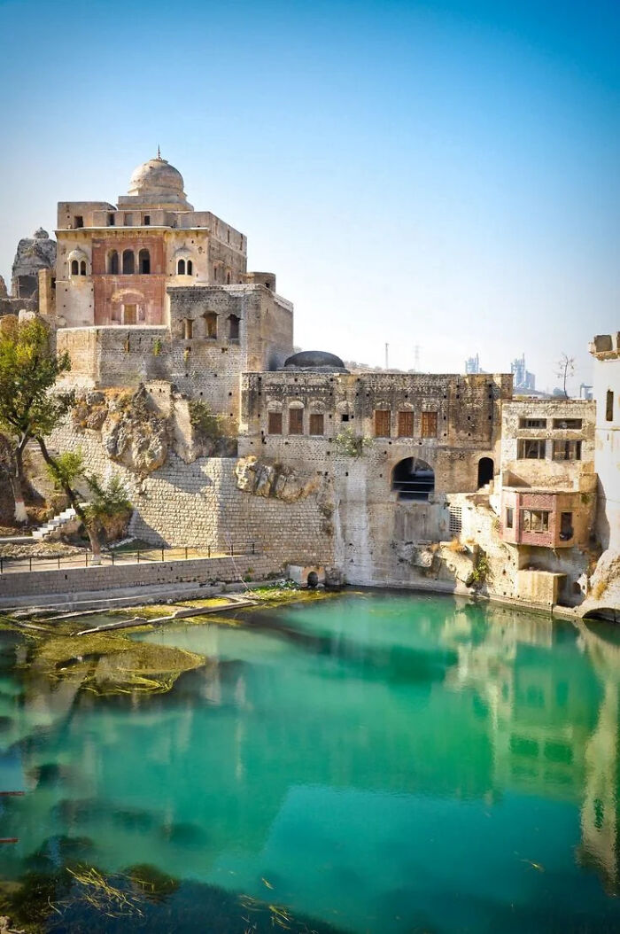 Ancient impressive architectural feats showcasing historic stone buildings beside a turquoise water body under clear skies.