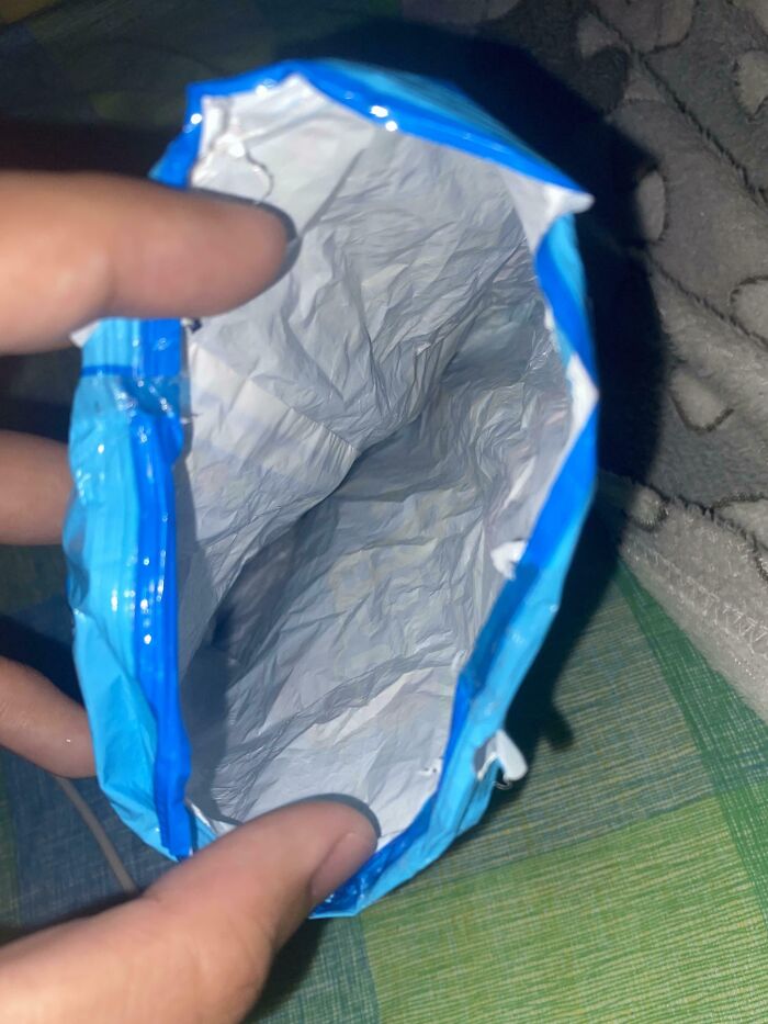 Empty chip bag held by fingers, demonstrating infuriating family member habits.