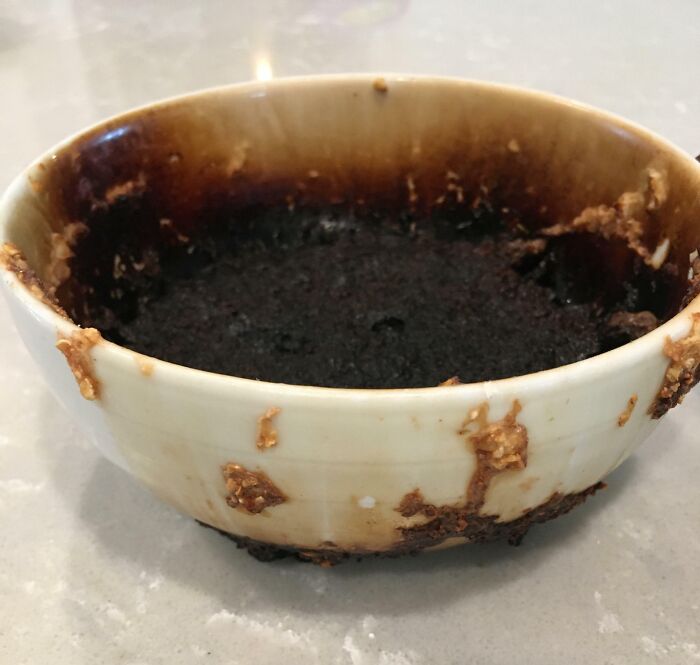A burnt bowl of food left by infuriating family members, covered in hardened residue, on a kitchen countertop.