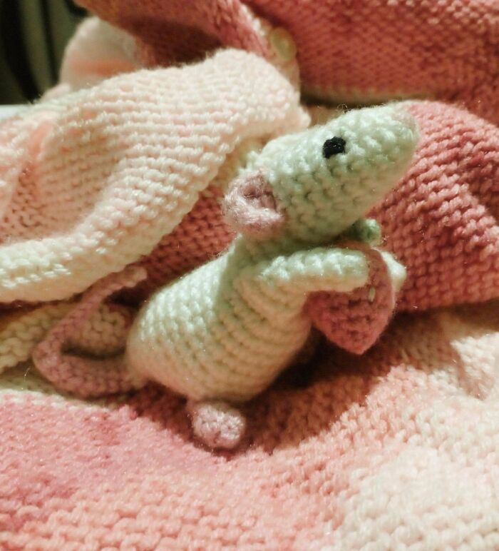 Crochet enthusiasts’ handmade amigurumi mouse nestled on a soft pink and white crocheted blanket showcasing detailed stitches.