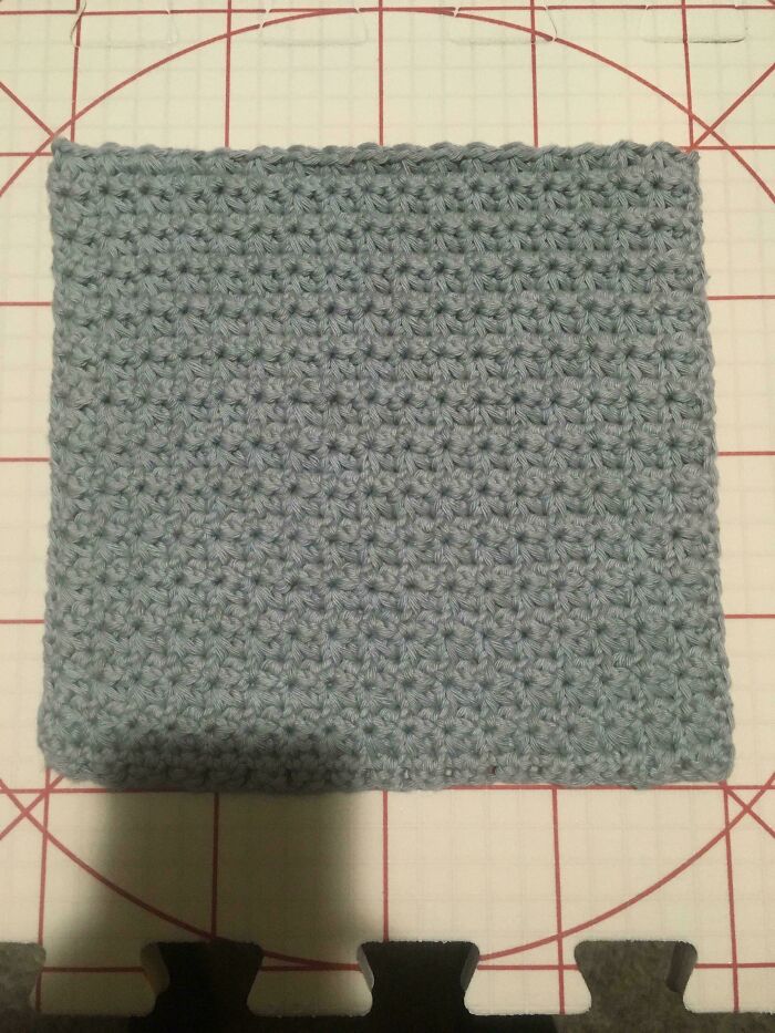 Light blue crochet square project on a cutting mat, showcasing detailed stitches by crochet enthusiasts.