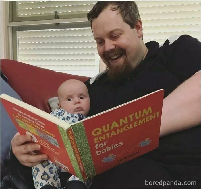 Man reading a "Quantum Entanglement for Babies" book to a surprised baby, highlighting science memes humor.
