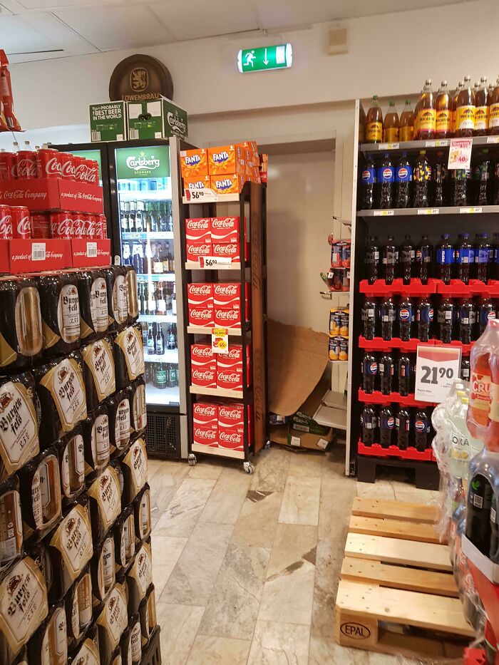 Grocery store aisle blocked by stacked soda crates, posing a safety hazard and ignoring safety protocol risks.