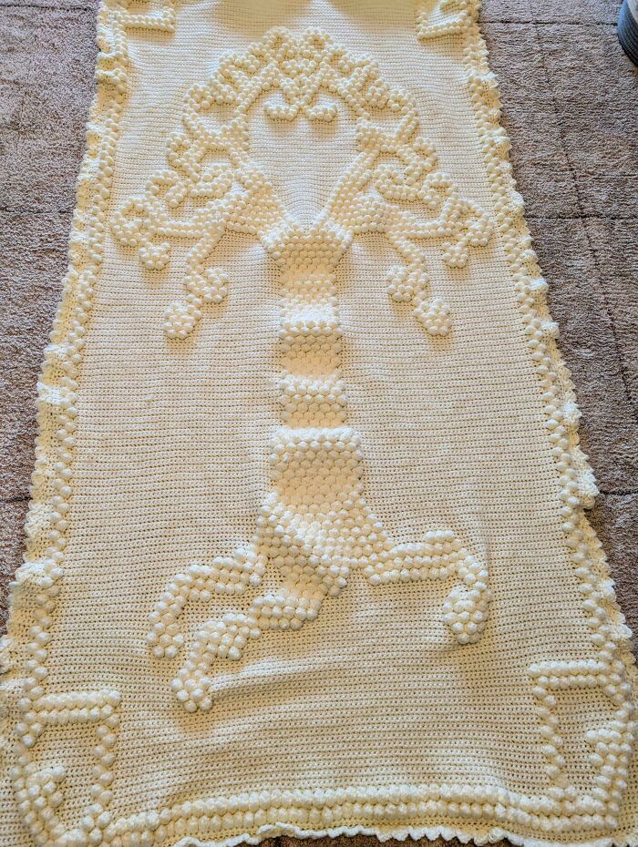 Crochet blanket featuring a raised textured tree pattern, showcasing the proud work of crochet enthusiasts.