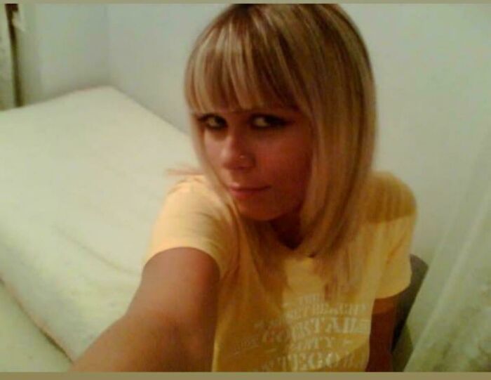 Woman taking a selfie during her "blunder years," wearing a yellow shirt and posing in a bedroom.
