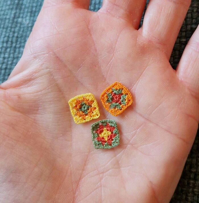 Tiny colorful crochet squares displayed on an open hand showcasing intricate crochet projects by enthusiasts.