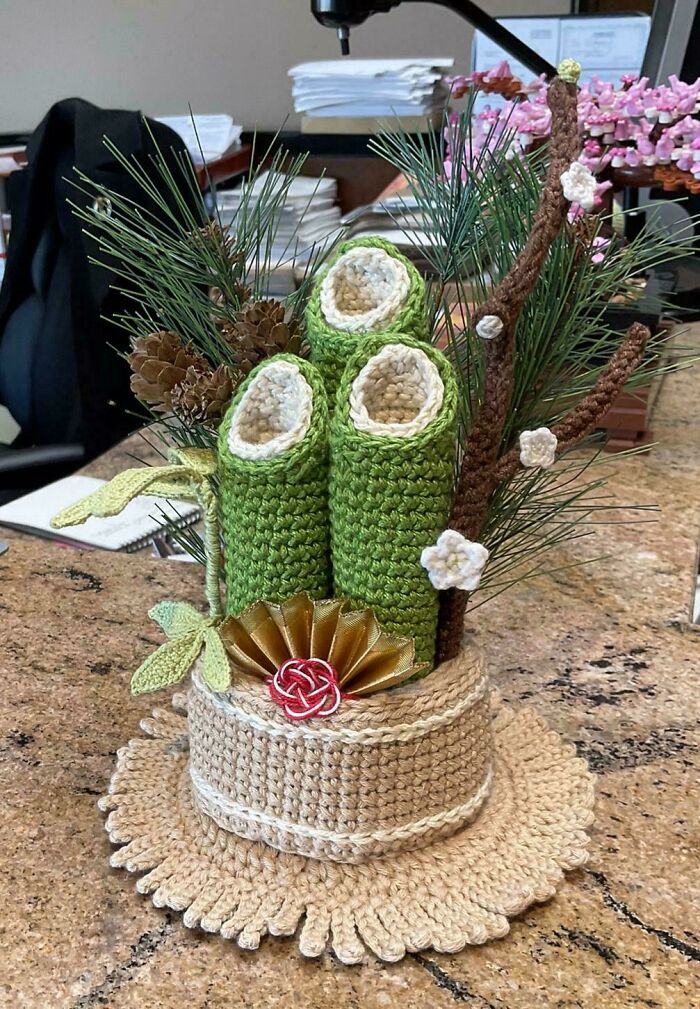 Crochet enthusiasts’ intricate green and beige handmade project featuring floral and pinecone details on a table.