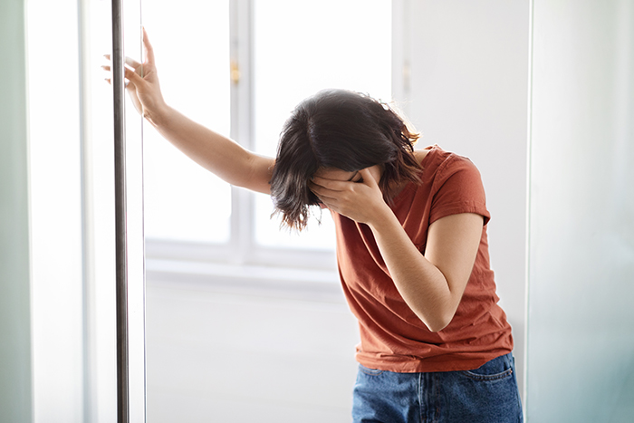 Stressed mom leaning against the wall in frustration, hand on her face. Stressed mom leaning against the wall in frustration, hand on her face.
