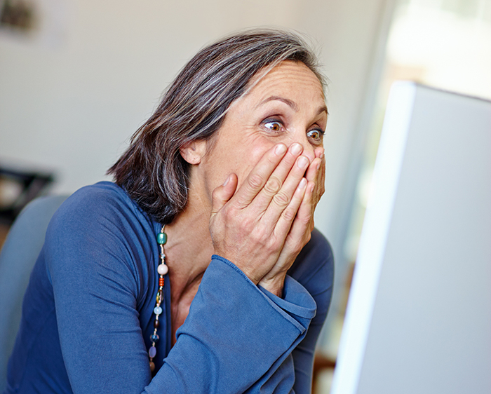 A surprised woman in front of a computer, reacting to a background check revelation. A surprised woman in front of a computer, reacting to a background check revelation.
