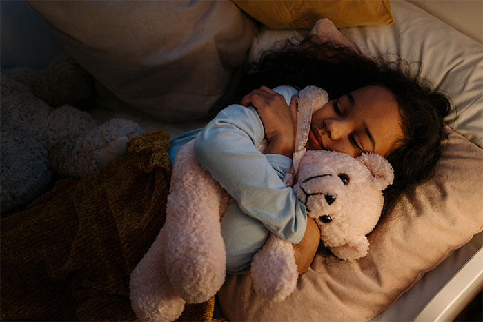 Child peacefully sleeping during holiday season, hugging a teddy bear in a cozy bed. Child peacefully sleeping during holiday season, hugging a teddy bear in a cozy bed.