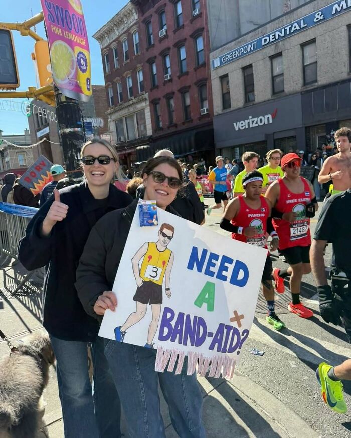 People at a New York marathon holding a funny sign saying "Need a Band-Aid?"