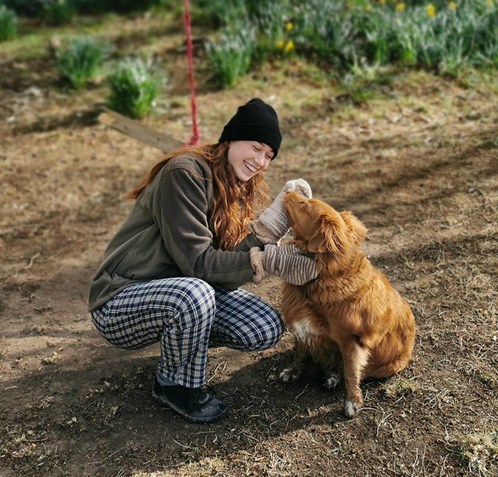 Dr. Ally Louks in a beanie plays with a dog outdoors. Dr. Ally Louks in a beanie plays with a dog outdoors.