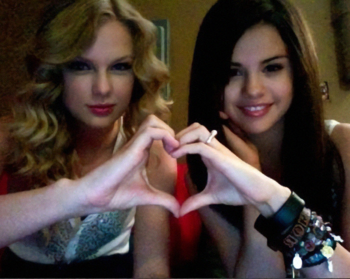 Selena Gomez and Taylor Swift forming a heart with their hands. Selena Gomez and Taylor Swift forming a heart with their hands.