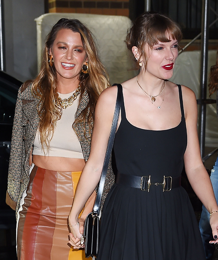 Blake Lively and Taylor Swift holding hands, one in a patterned jacket and skirt, the other in a black dress. Blake Lively and Taylor Swift holding hands, one in a patterned jacket and skirt, the other in a black dress.