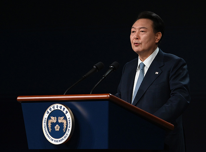 South Korea's president giving a speech, standing at a podium against a dark backdrop, related to martial law declaration. South Korea's president giving a speech, standing at a podium against a dark backdrop, related to martial law declaration.