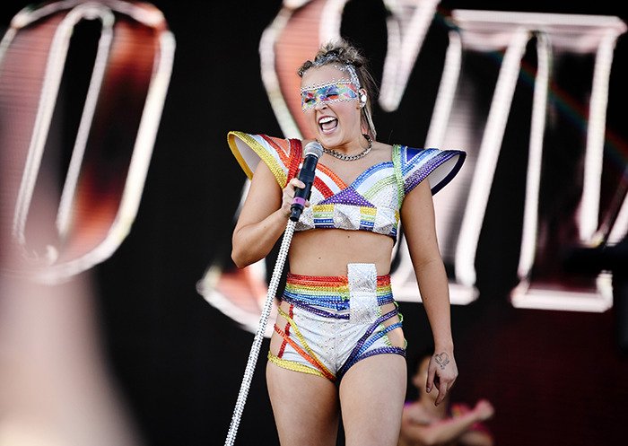 JoJo Siwa performing on stage in a colorful outfit, holding a microphone. JoJo Siwa performing on stage in a colorful outfit, holding a microphone.