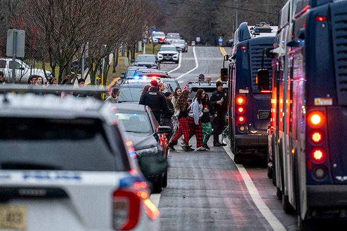 Police presence and buses on the street after Wisconsin school tragedy, with people gathered near vehicles. Police presence and buses on the street after Wisconsin school tragedy, with people gathered near vehicles.