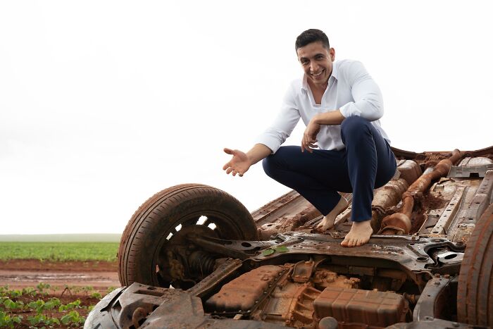 Man posing with overturned car at accident scene. Man posing with overturned car at accident scene.