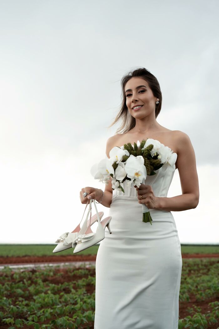 Bride holding shoes and flowers, smiling after a car accident, photo shoot at the accident scene. Bride holding shoes and flowers, smiling after a car accident, photo shoot at the accident scene.