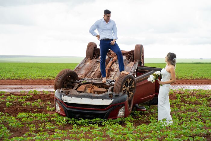 Couple takes photos beside overturned car in a field after accident on way to photo shoot. Couple takes photos beside overturned car in a field after accident on way to photo shoot.