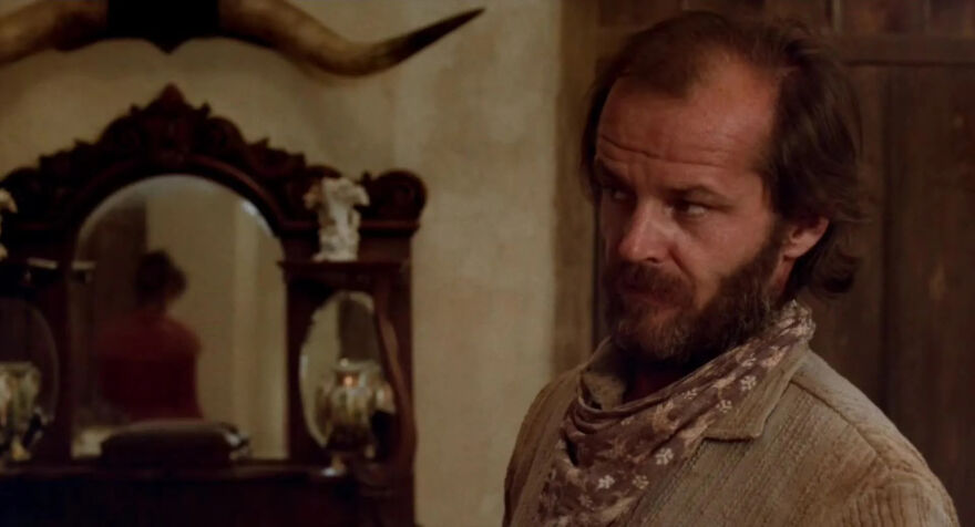 Actor Jack Nicholson in rugged attire in front of ornate mirror and mounted horns, embodying his usual self in film.