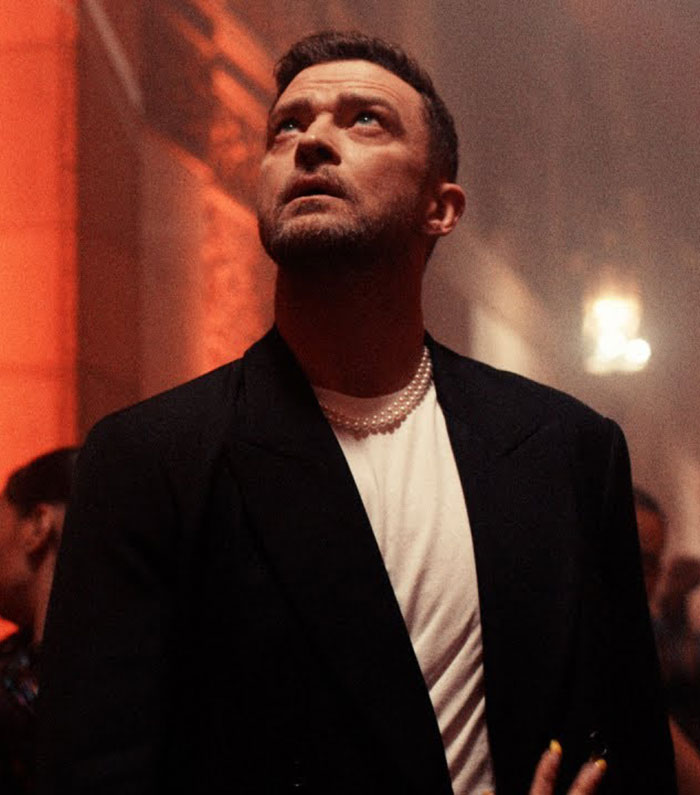 Justin Timberlake in a dark blazer and white shirt with a thoughtful look amidst a softly lit background. Justin Timberlake in a dark blazer and white shirt with a thoughtful look amidst a softly lit background.