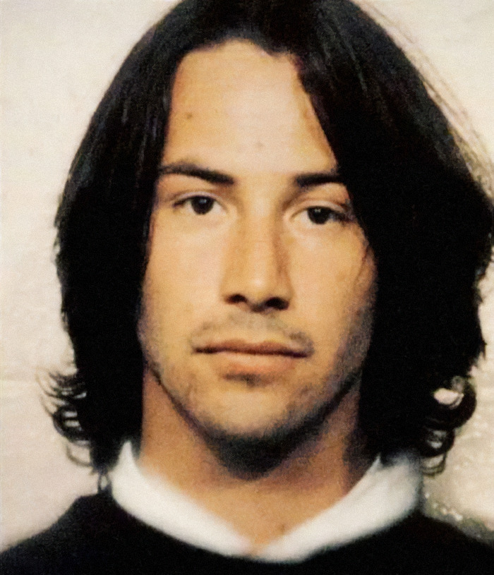 A mugshot featuring actor Keanu Reeves with long dark hair and a serious expression. A mugshot featuring actor Keanu Reeves with long dark hair and a serious expression.