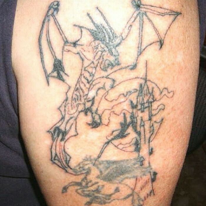 Poorly drawn dragon tattoo fail with distorted wings and castle.
