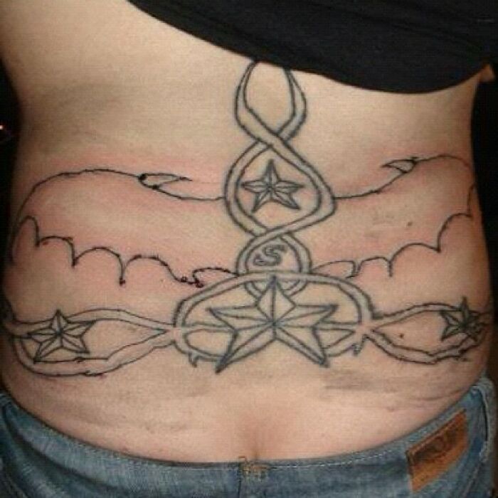 Worst tattoo fails on a person's lower back with unfinished lines and stars.
