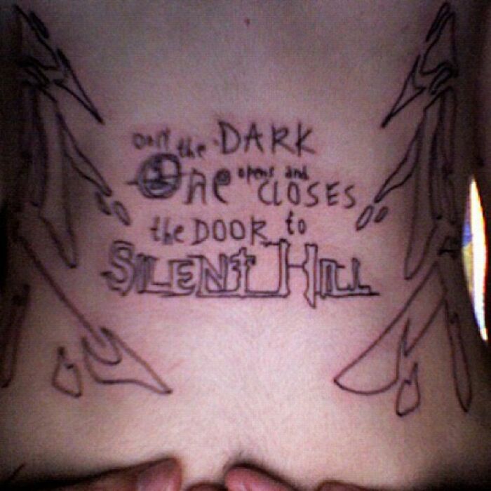 Bad tattoo of Silent Hill quote on lower back with awkward design.