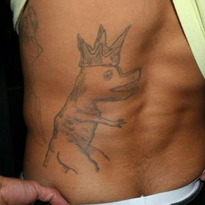 Tattoo fail featuring a poorly drawn crowned creature on a person's side.