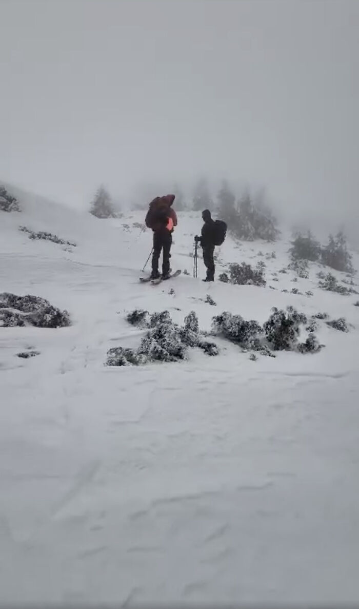 Two hikers on snowy mountain terrain, one with a backpack, in foggy conditions. Two hikers on snowy mountain terrain, one with a backpack, in foggy conditions.