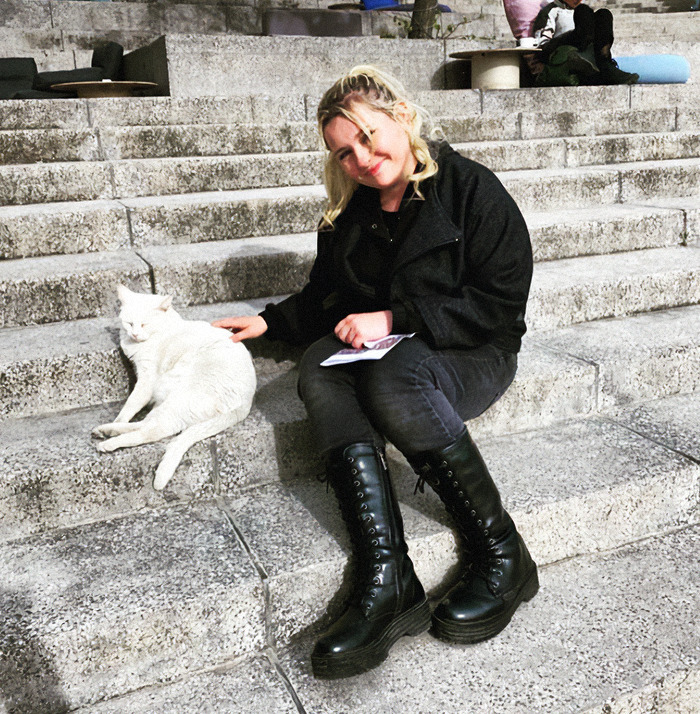 Abigail Breslin sitting on steps, petting a white cat. Abigail Breslin sitting on steps, petting a white cat.