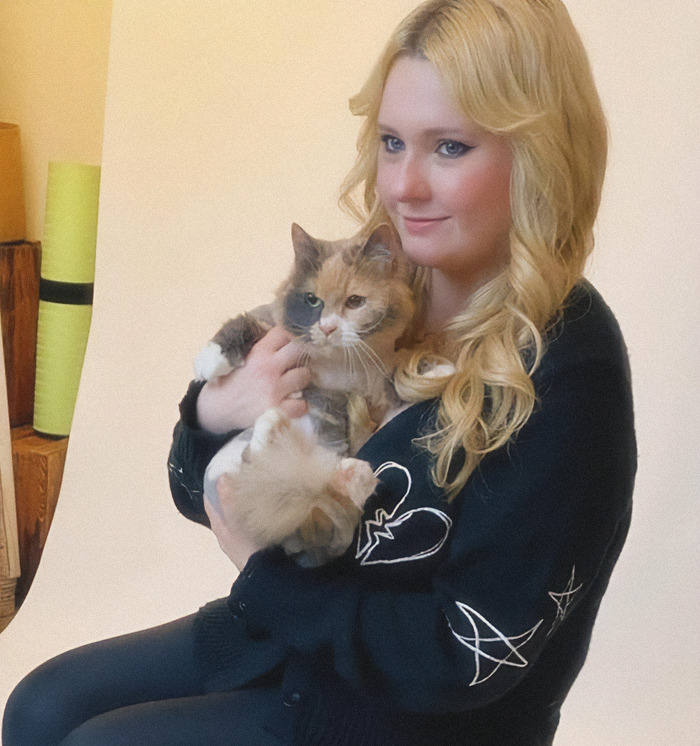Abigail Breslin holding a cat, smiling gently at the camera. Abigail Breslin holding a cat, smiling gently at the camera.