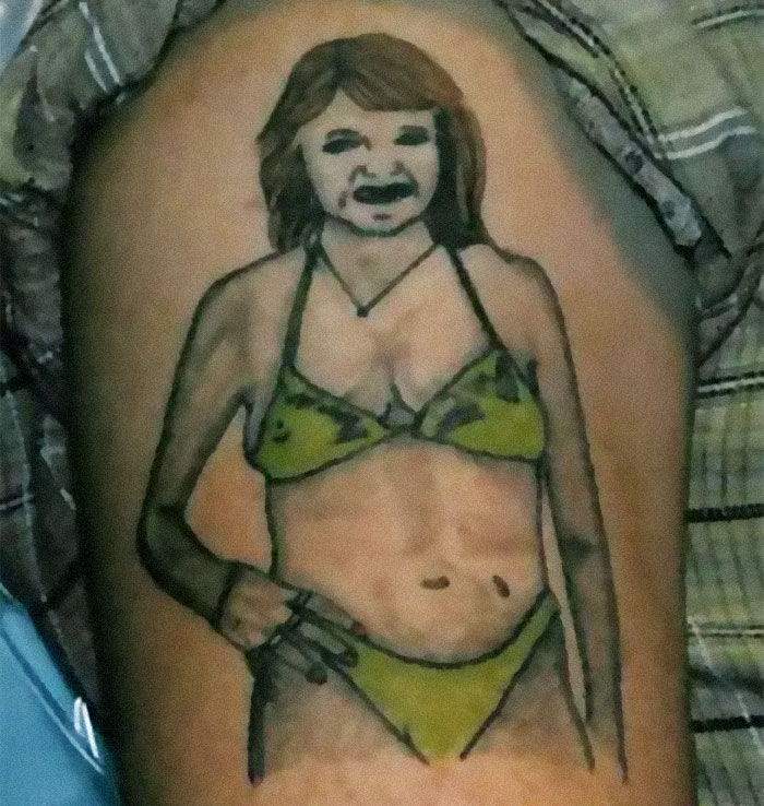 Tattoo fail of a woman in a green bikini with a distorted face on a person's arm.