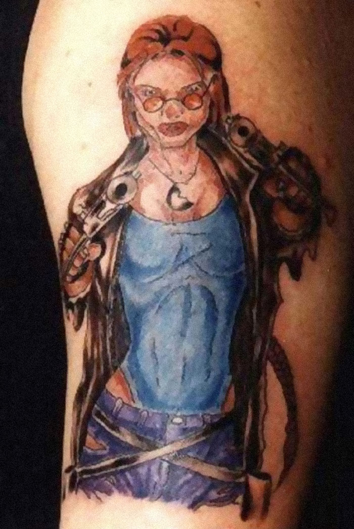 Tattoo fail featuring an oddly shaped superhero with sunglasses on a person's arm.