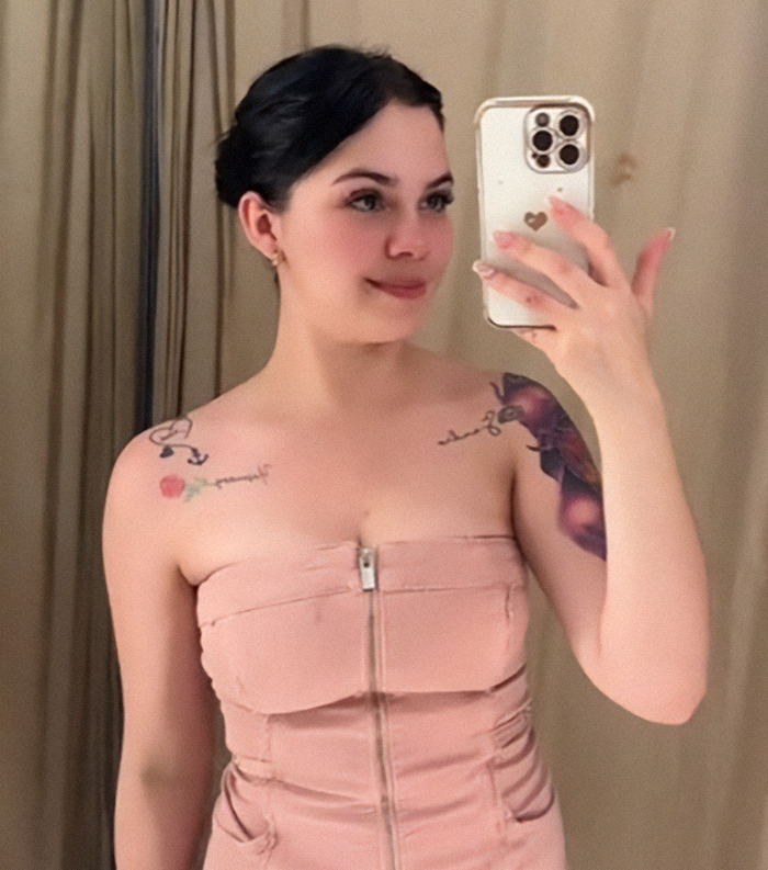 Nebrazkha in pink dress takes a mirror selfie, tattoos visible on shoulders. Nebrazkha in pink dress takes a mirror selfie, tattoos visible on shoulders.